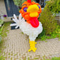 Balloon sculpture of a rooster in front of a house