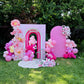 Decorative archway with pink and white balloons and flowers in a garden setting