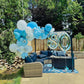 Outdoor setting with blue and white balloons and a '80' sign in a garden.