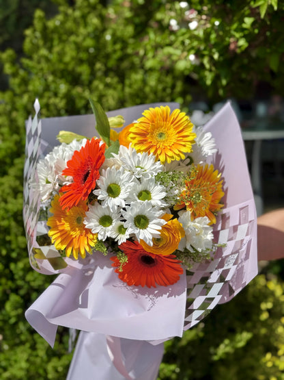 Bouquet of orange, yellow, and white flowers wrapped in paper. Mother's day present in Toronto.