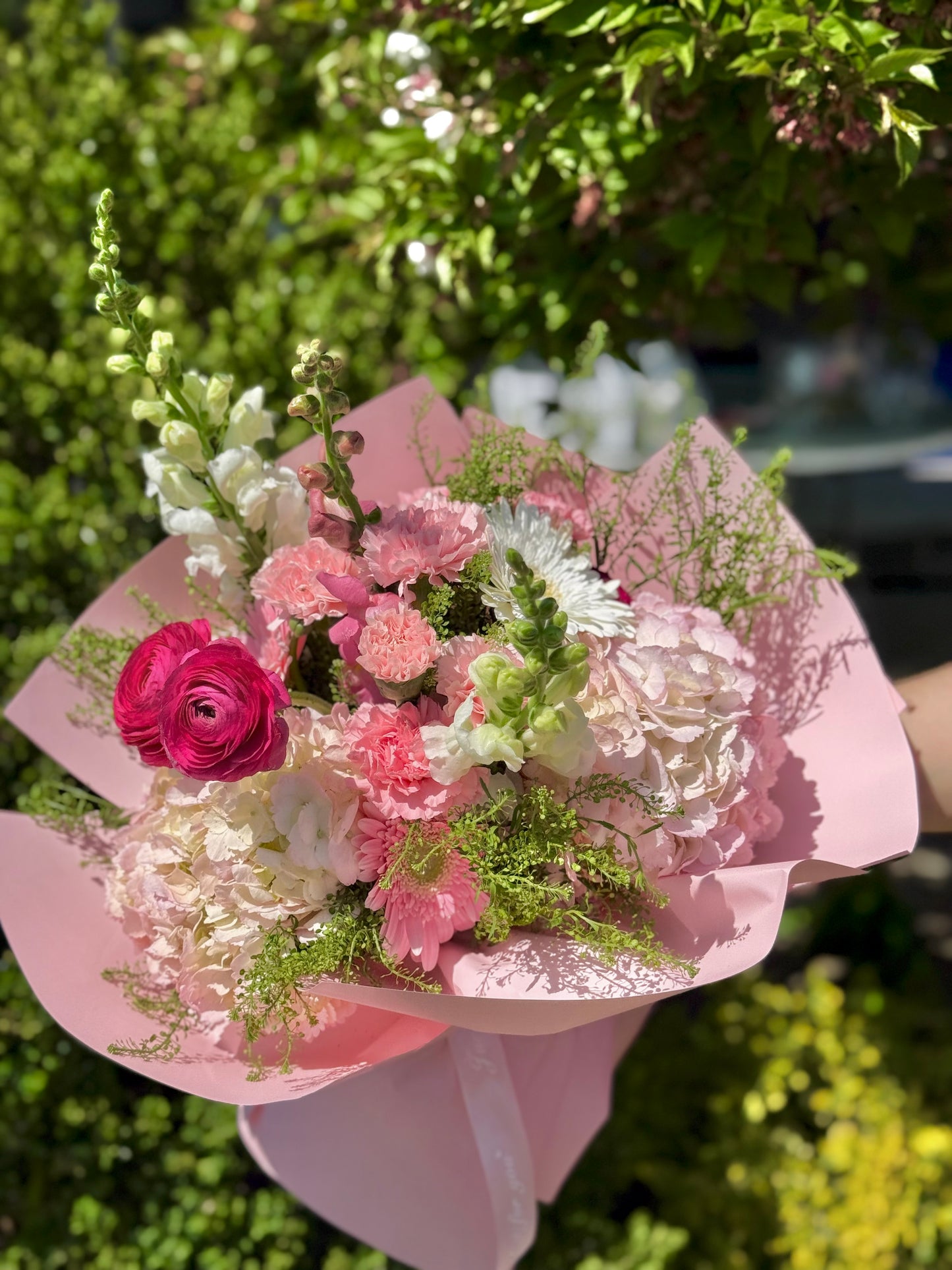 Bouquet of pink flowers in a pink wrapping held by Wooow Balloons Toronto