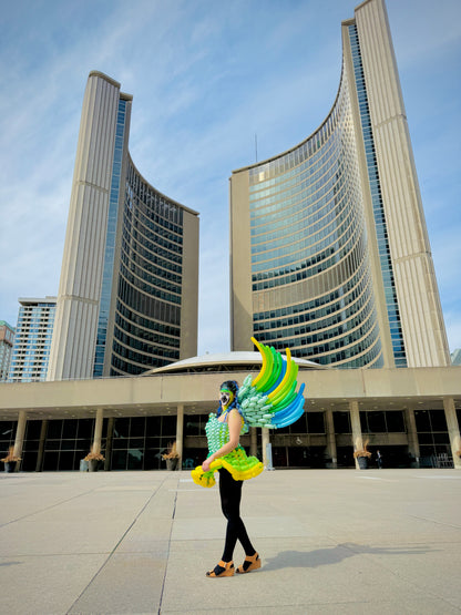 Person with colorful costume standing in front of a large building
