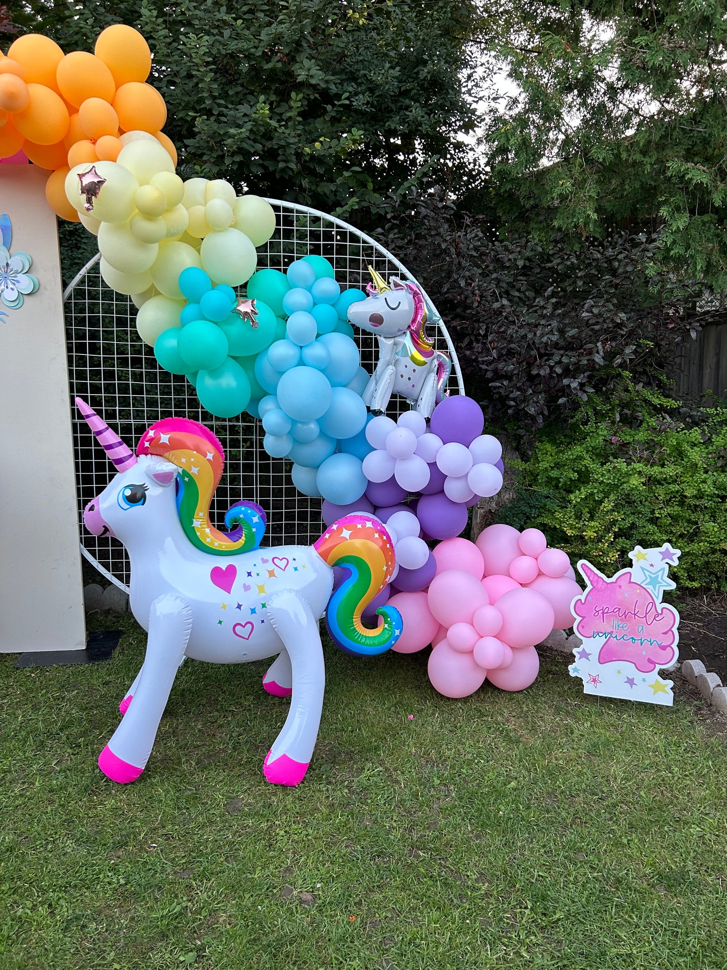 Magical Unicorn Balloon Backdrop with a pastel rainbow balloon arch and inflatable unicorn decorations for a kids’ party.