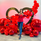 Romantic balloon decor with a gold heart rental, red balloons, floral embellishments, and mirror balls. A woman forms a heart shape with her hands