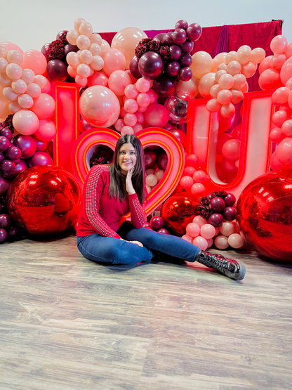 Luxury 'I ❤️ U' balloon installation with a red and blush balloon garland, floral accents, and oversized metallic spheres.