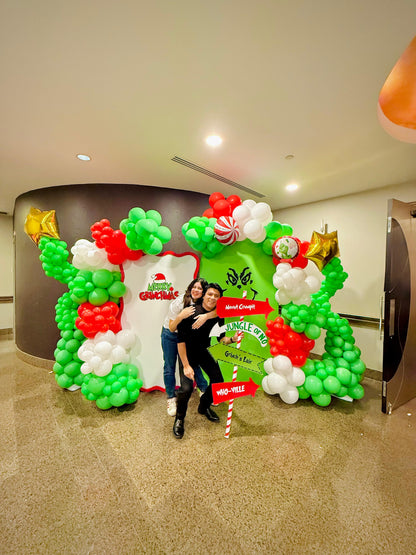 Grinch balloon decor setup with festive balloon garlands and backdrops.

