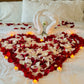 Heart made of fresh rose petals on bed with swan towels – romantic hotel decor in Toronto