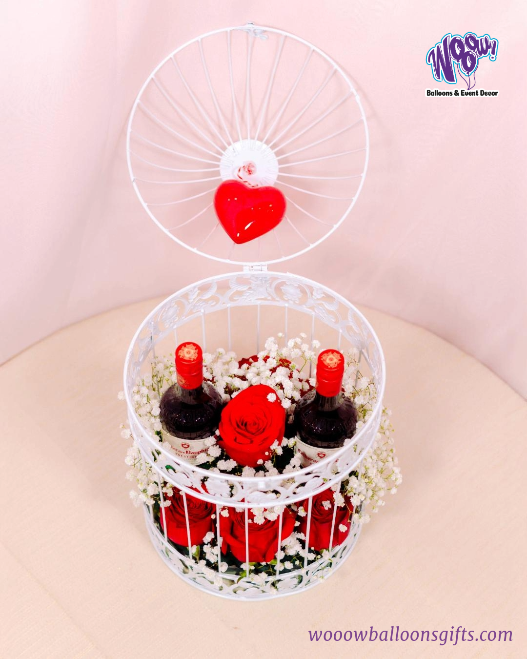 Romantic Cage Gift Set with fresh roses, baby’s breath flowers, and wine bottles inside an elegant white metal birdcage.