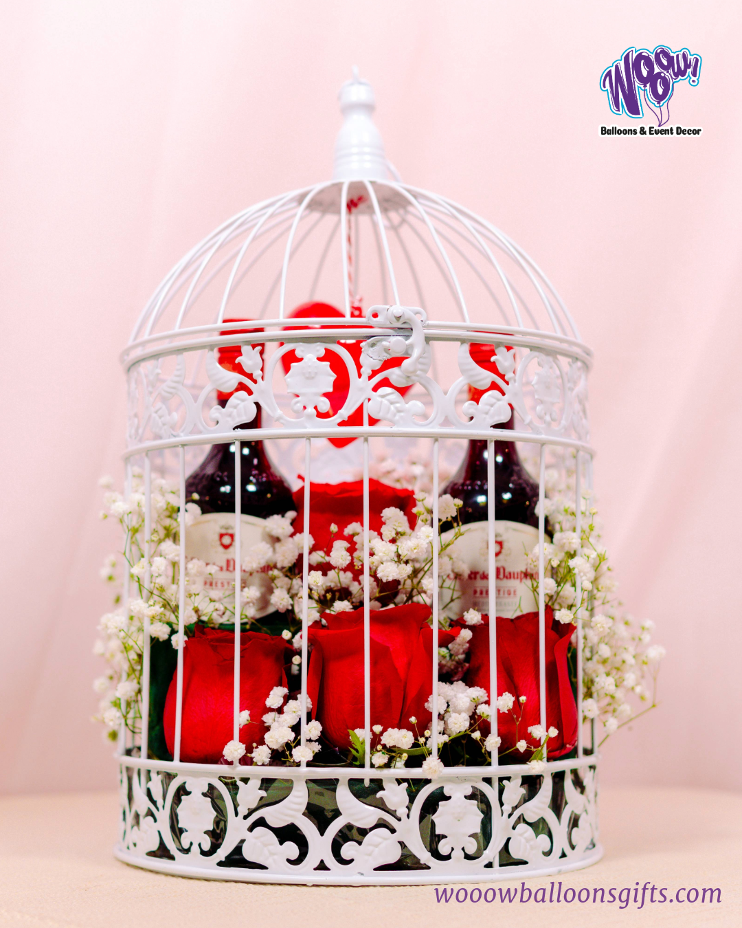 Romantic Cage Gift Set with fresh roses, baby’s breath flowers, and wine bottles inside an elegant white metal birdcage.