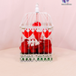 Lovebird Rose Cage with fresh red roses inside a vintage-inspired white birdcage with heart decorations.