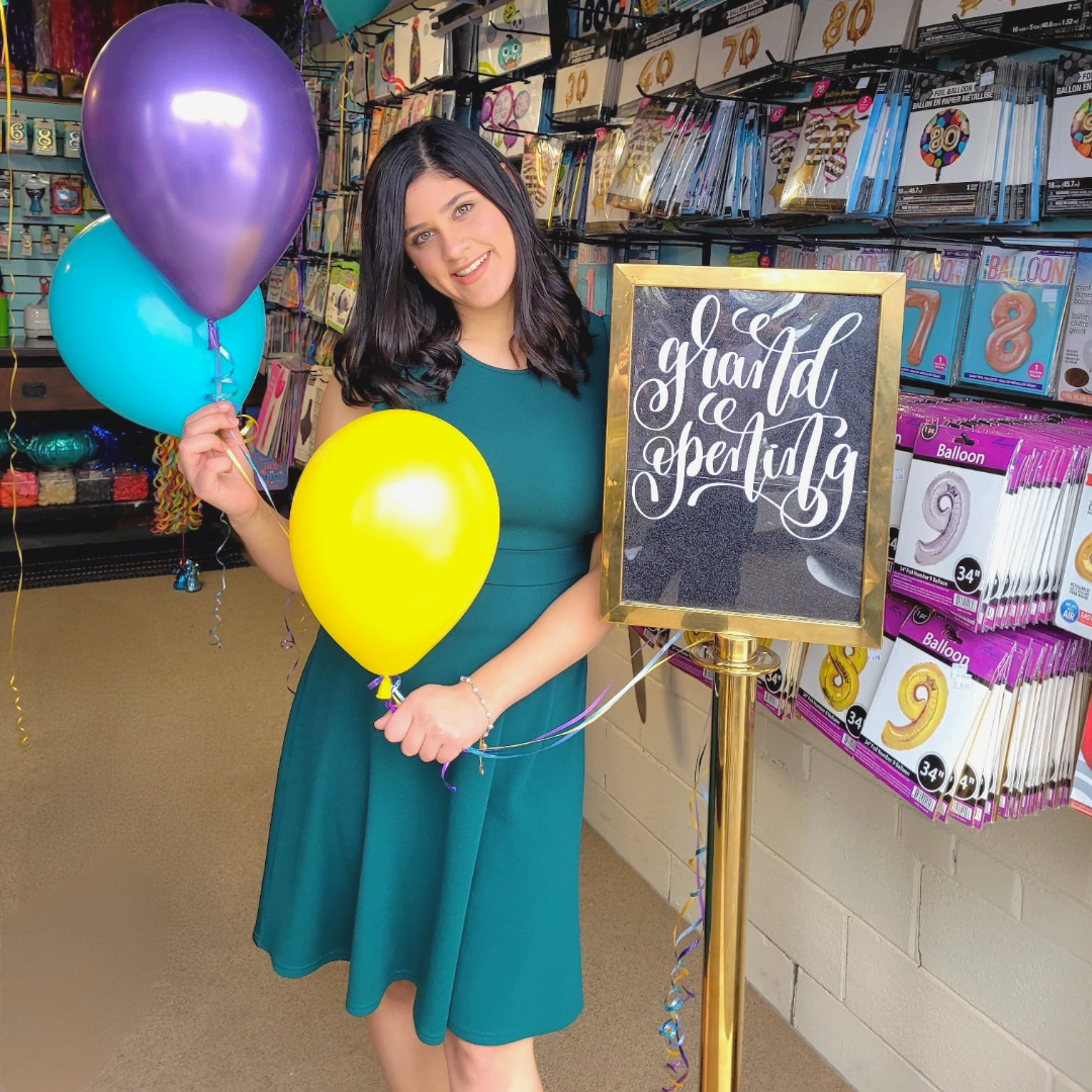 Woman holding balloons in a store with a 'gravid or spectabilis' sign.