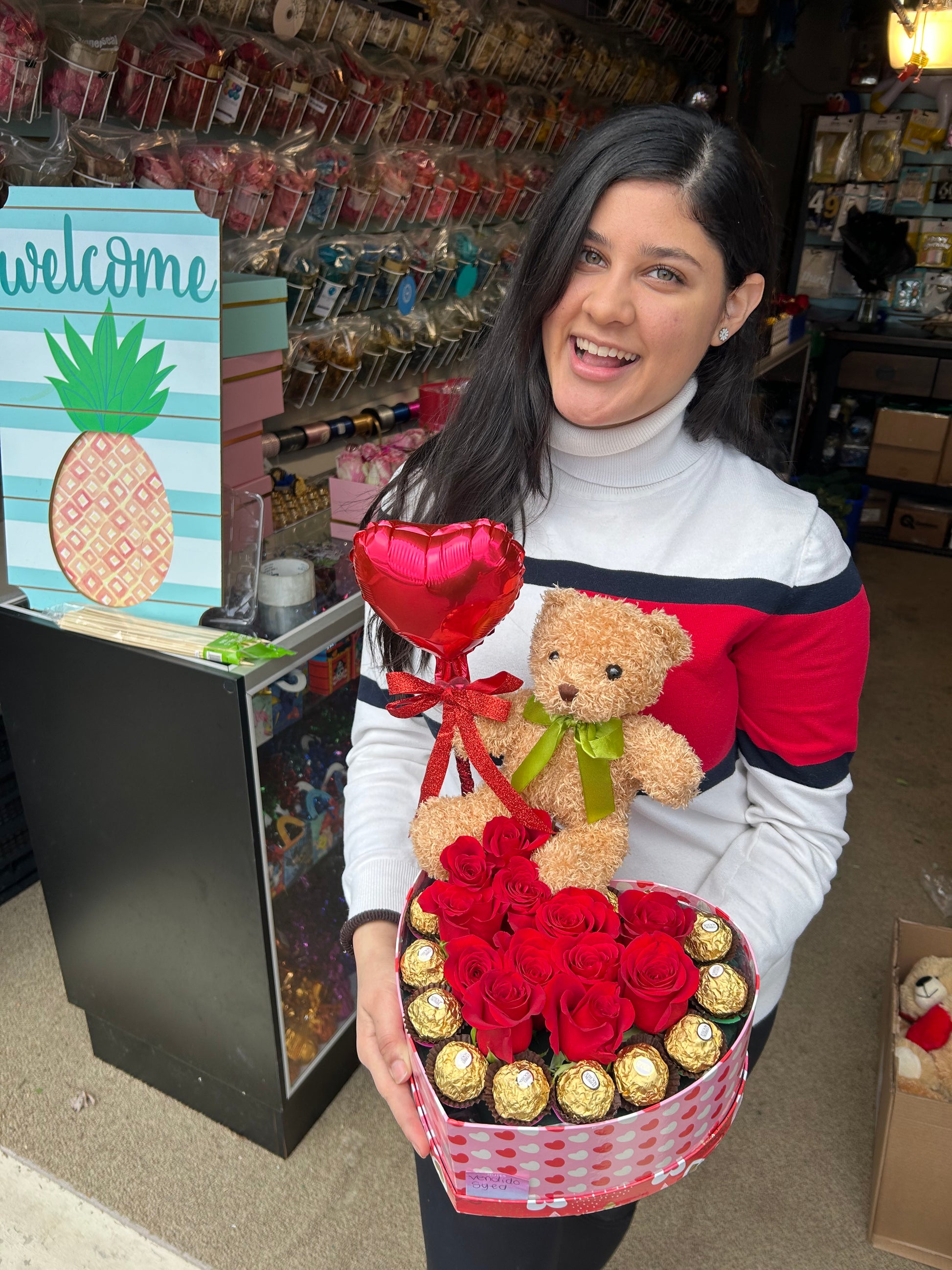 Heart-shaped gift box with roses, Ferrero Rocher chocolates, a small red balloon, and a teddy bear.