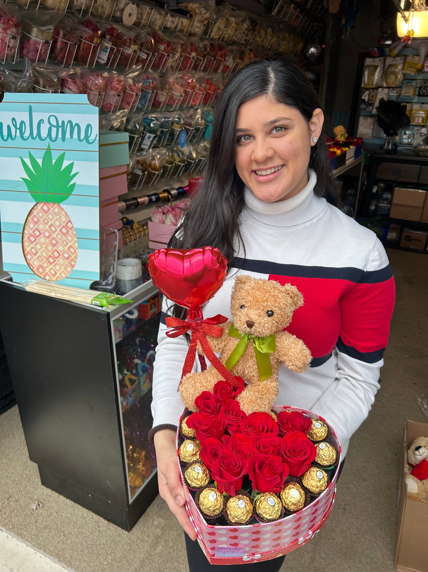 Heart-shaped gift box with roses, Ferrero Rocher chocolates, a small red balloon, and a teddy bear.