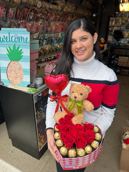 Heart-shaped gift box with roses, Ferrero Rocher chocolates, a small red balloon, and a teddy bear.