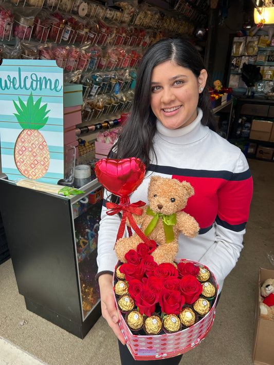 Heart-shaped gift box with roses, Ferrero Rocher chocolates, a small red balloon, and a teddy bear.