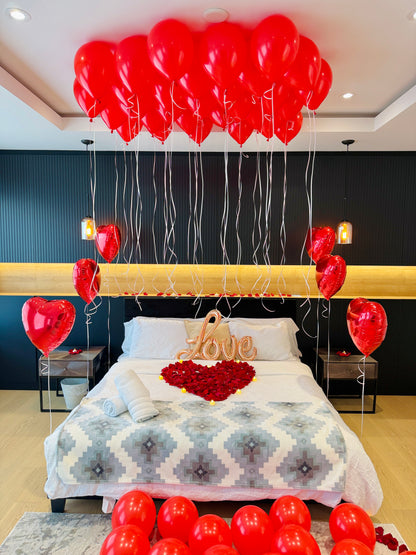 Anniversary room decor with red heart balloons rose petals and warm LED candles in Toronto