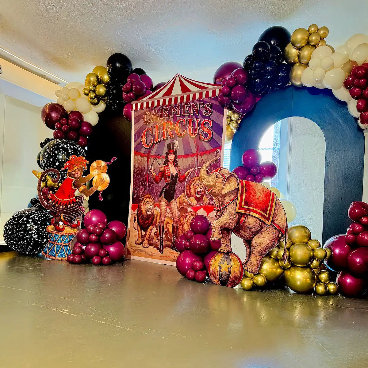 Personalized circus birthday balloon backdrop with black, magenta and gold garlands and animal props in Toronto.