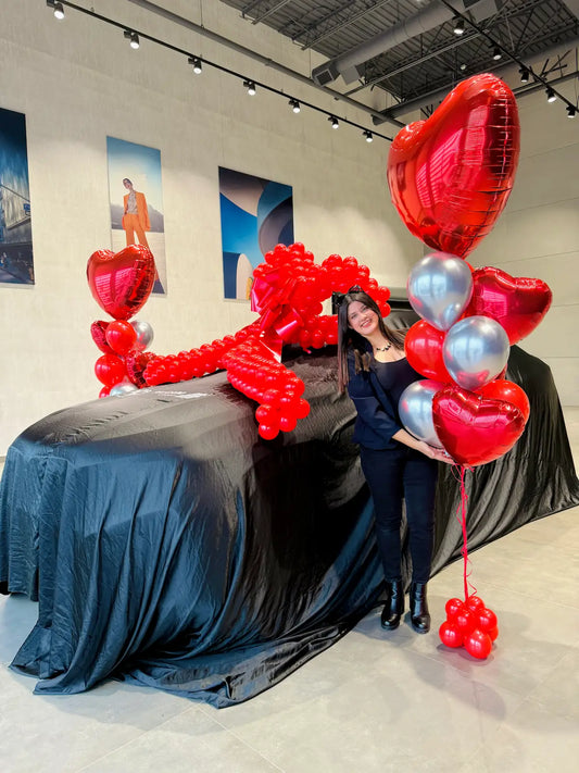 BMW car reveal decoration with a giant red balloon bow and red and silver heart bouquets by Wooow Balloons Toronto.