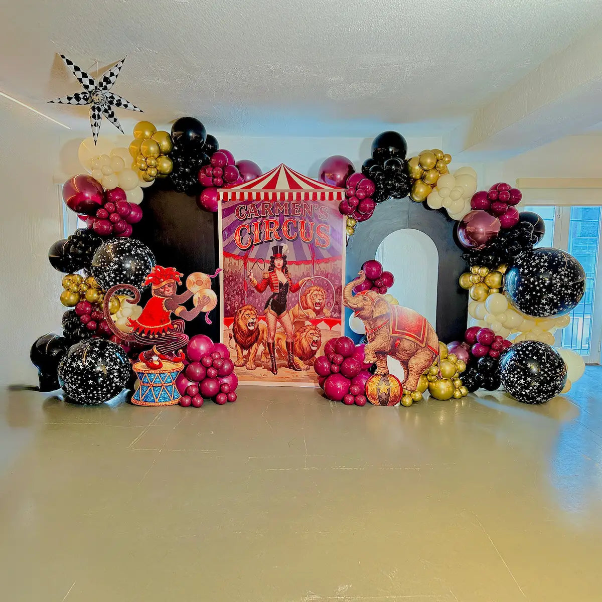 Circus-themed balloon backdrop with black, magenta, gold and ivory balloon garlands for a party in Toronto.