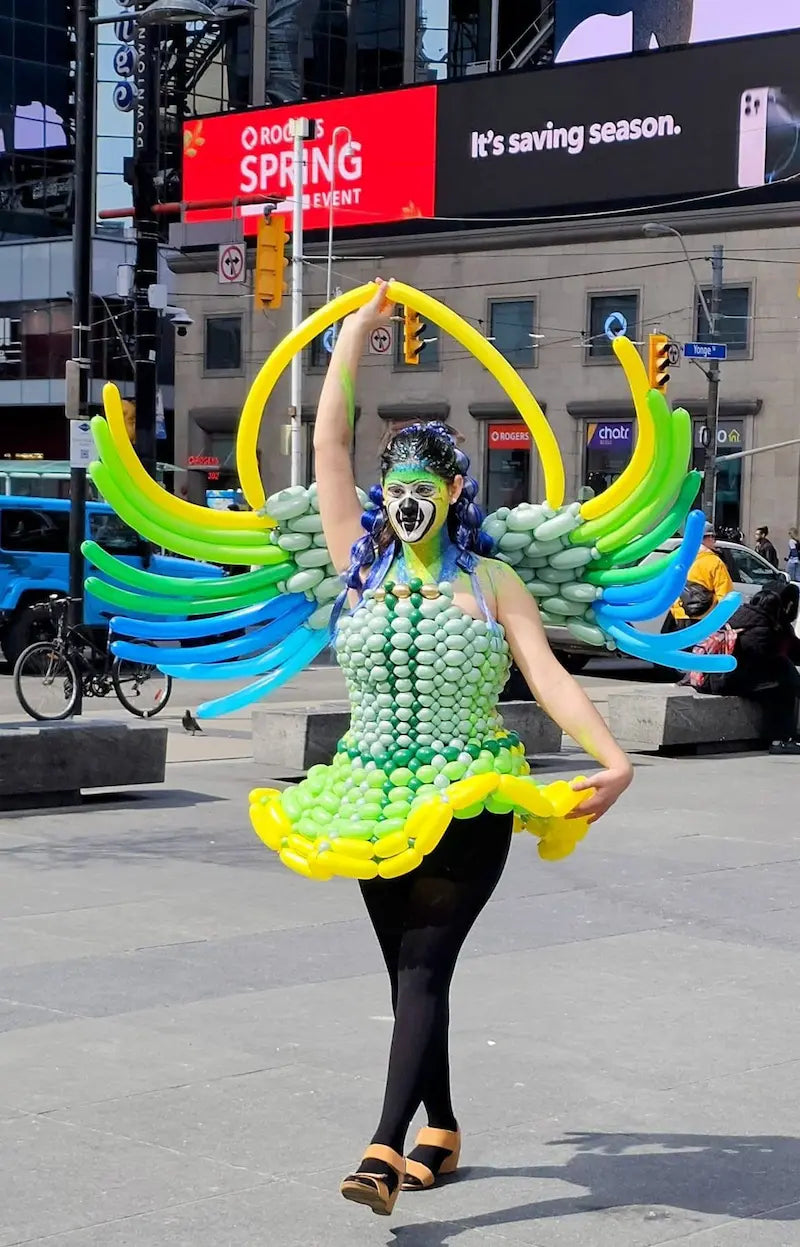 Wooow Balloons artist wearing a custom green and blue winged balloon dress on Yonge Street in downtown Toronto