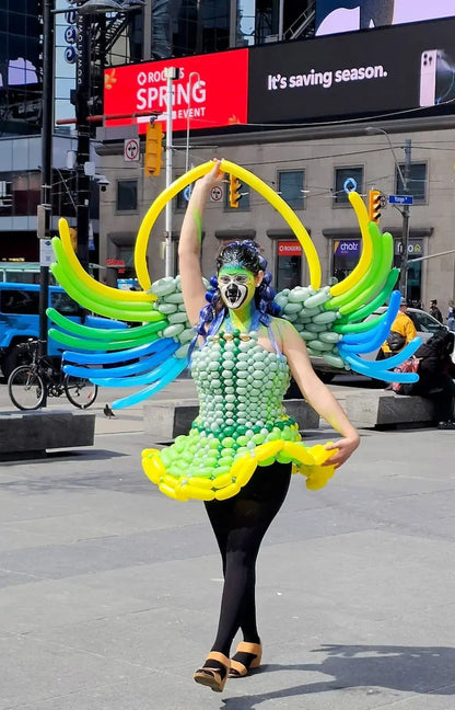 Wooow Balloons artist wearing a custom green and blue winged balloon dress on Yonge Street in downtown Toronto