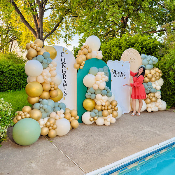 Decorative balloon arch with 'Congrats' and '2026' signs, outdoors by a pool.