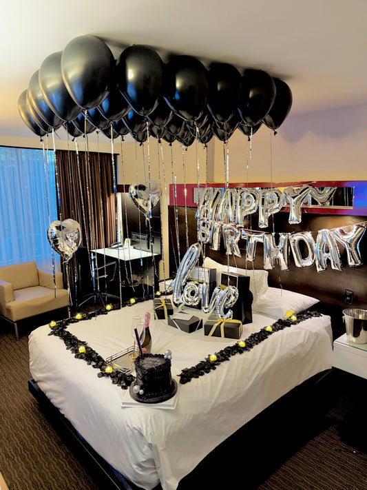 Luxury hotel room birthday decor with black helium balloons and glam celebration setup