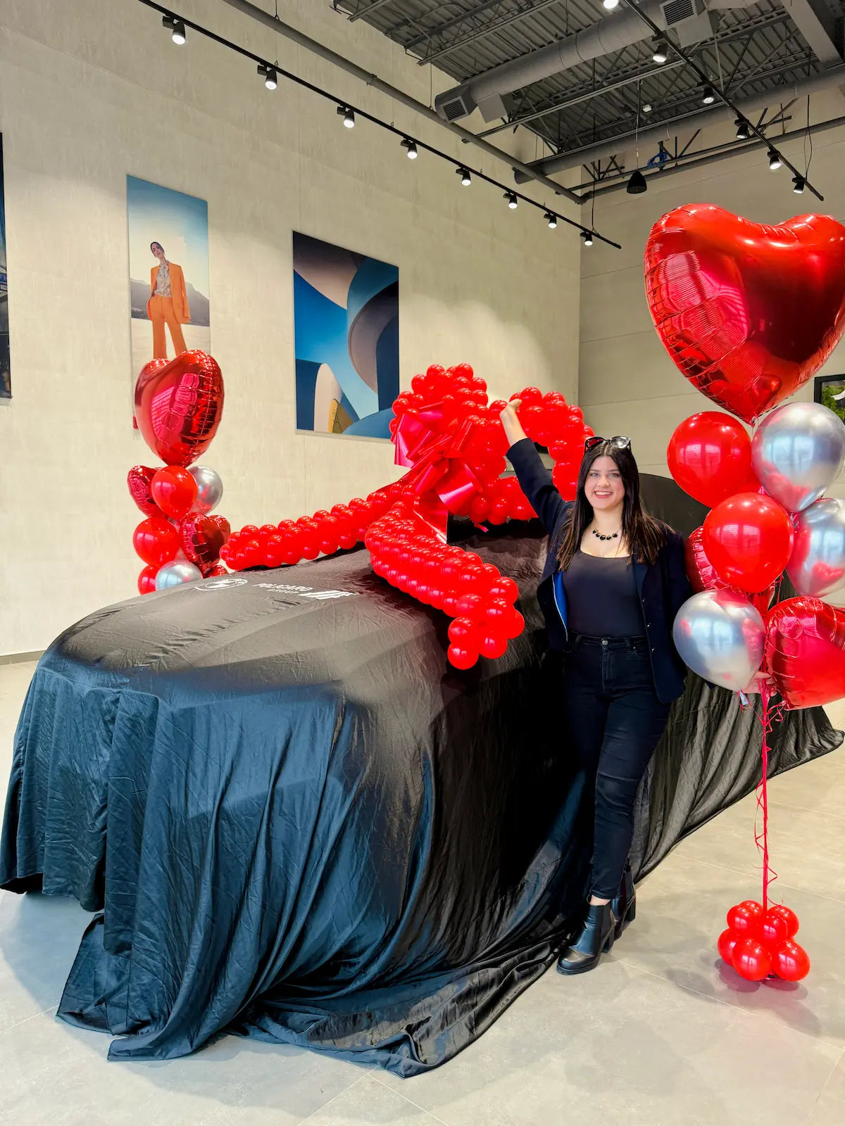 Luxury car reveal decoration with a giant red balloon bow and heart balloon bouquets by Wooow Balloons Toronto.
