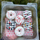 Decorative donuts in a clear container with a heart-patterned paper on a natural background