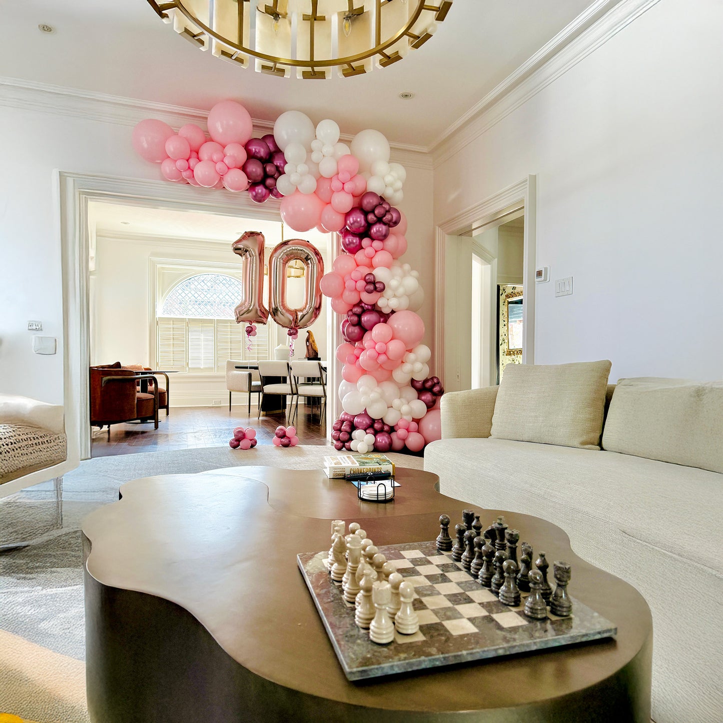 Decorated living room with balloons, number 10, and chessboard on a coffee table.