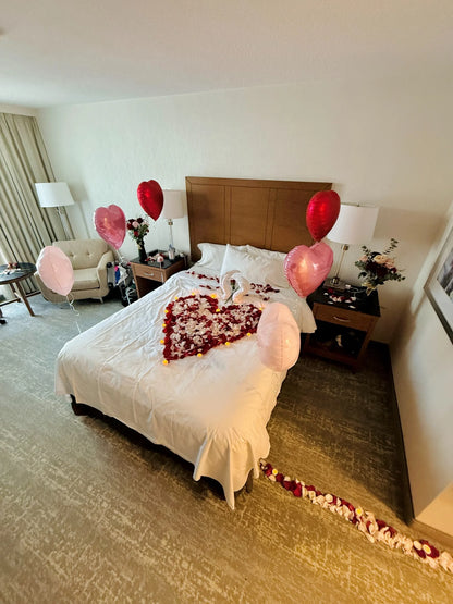 Romantic surprise setup with pink and red balloons, rose petals, and candles in Toronto