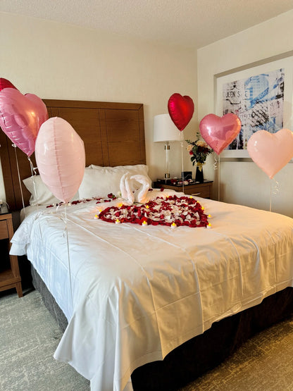 Romantic bed decoration with heart balloons, petals, and LED candles – perfect for anniversaries in Toronto