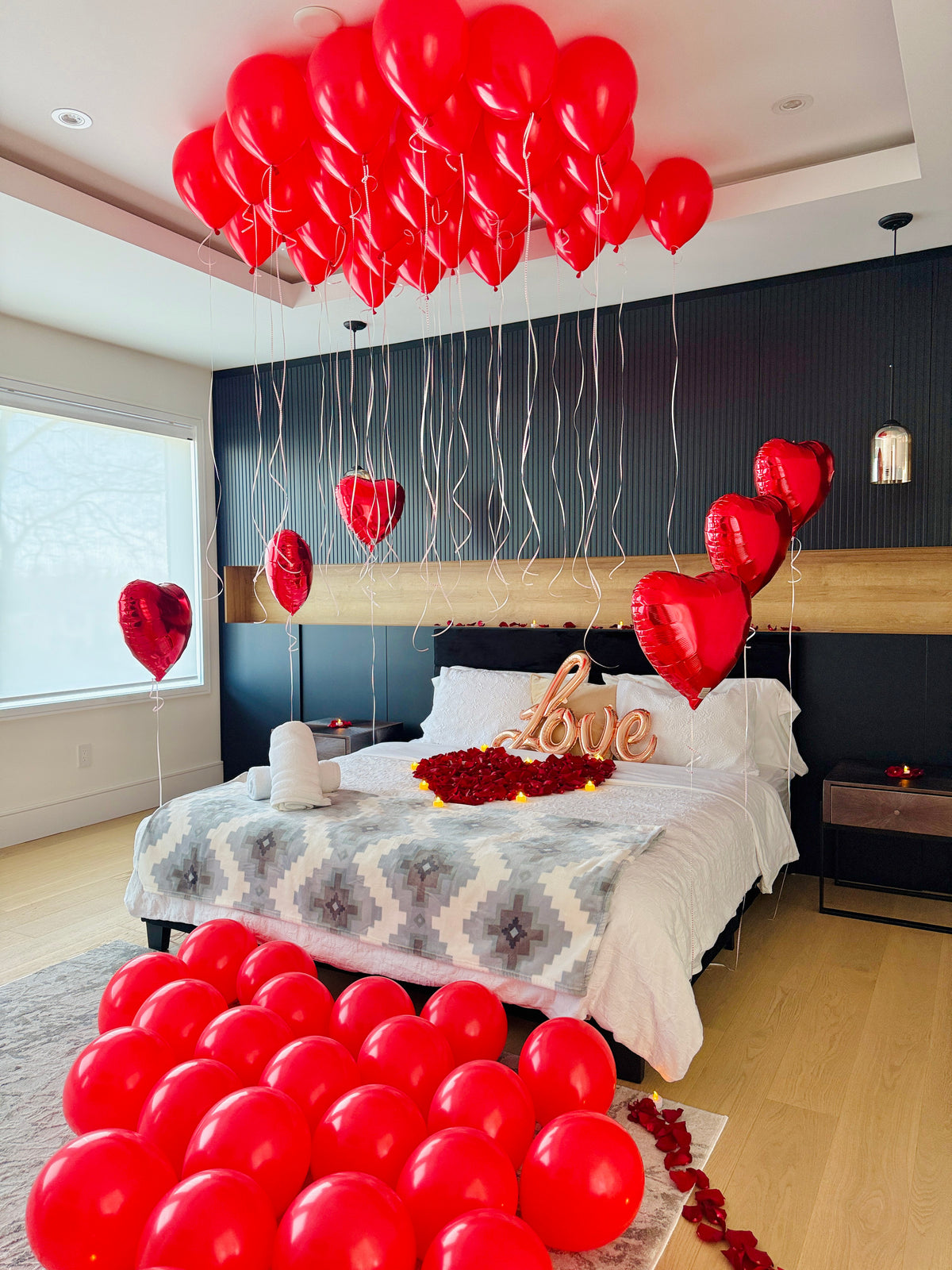 Romantic room decor Toronto with red ceiling balloons heart balloons rose petals LOVE sign and LED candles