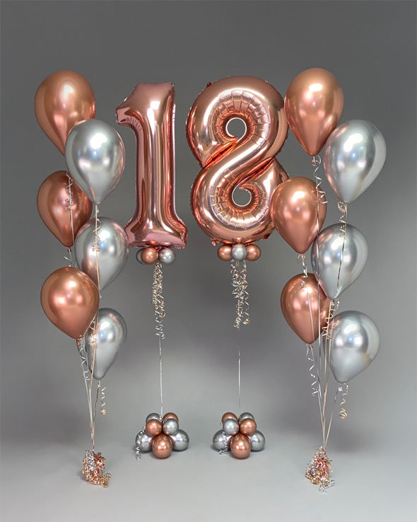 Rose gold and silver balloons with a large '18' balloon on a gray background